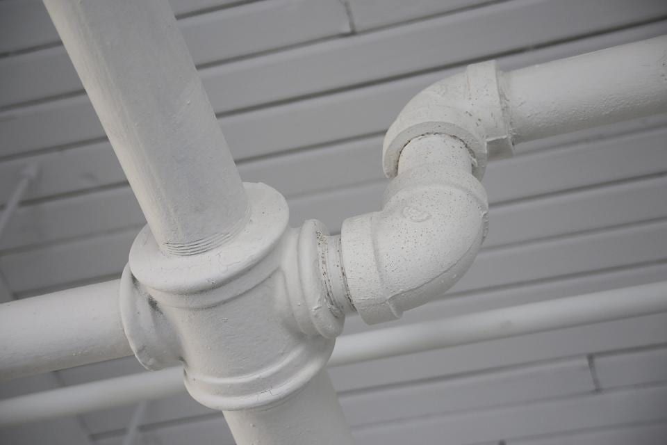 White-painted pipe elbows and fittings on a wall